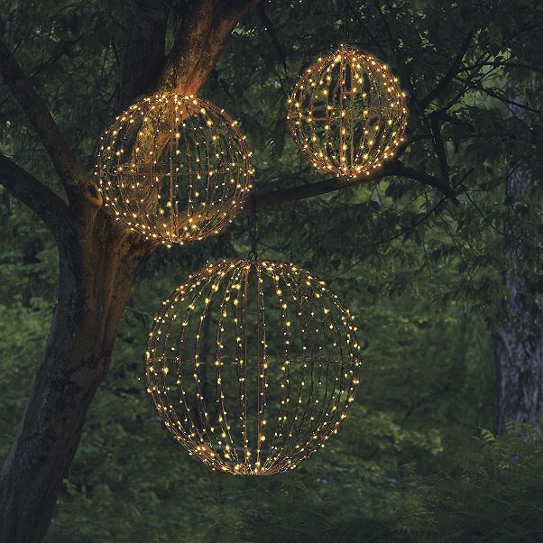 Three spherical fixtures with twinkle lights hanging from tree branches